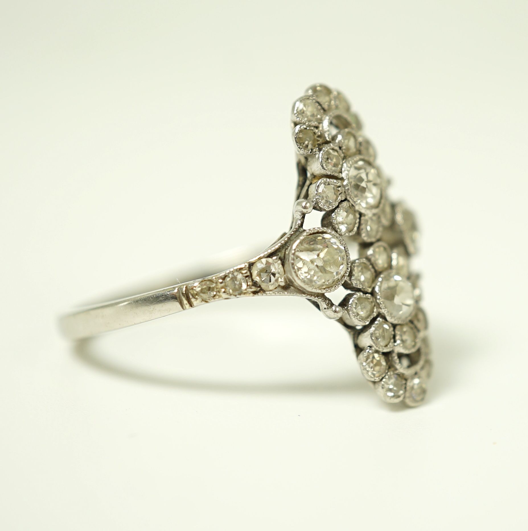 A 1920's platinum and millegrain diamond set flower head cluster upfinger ring